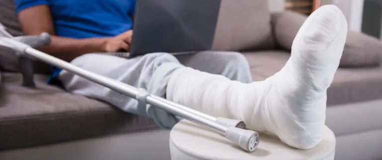 Man with broken foot in case resting on a stool