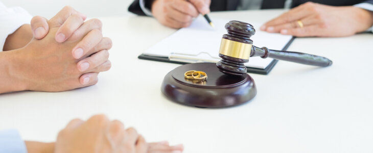 Couple meeting with divorce lawyer, wedding bands on the gavel.