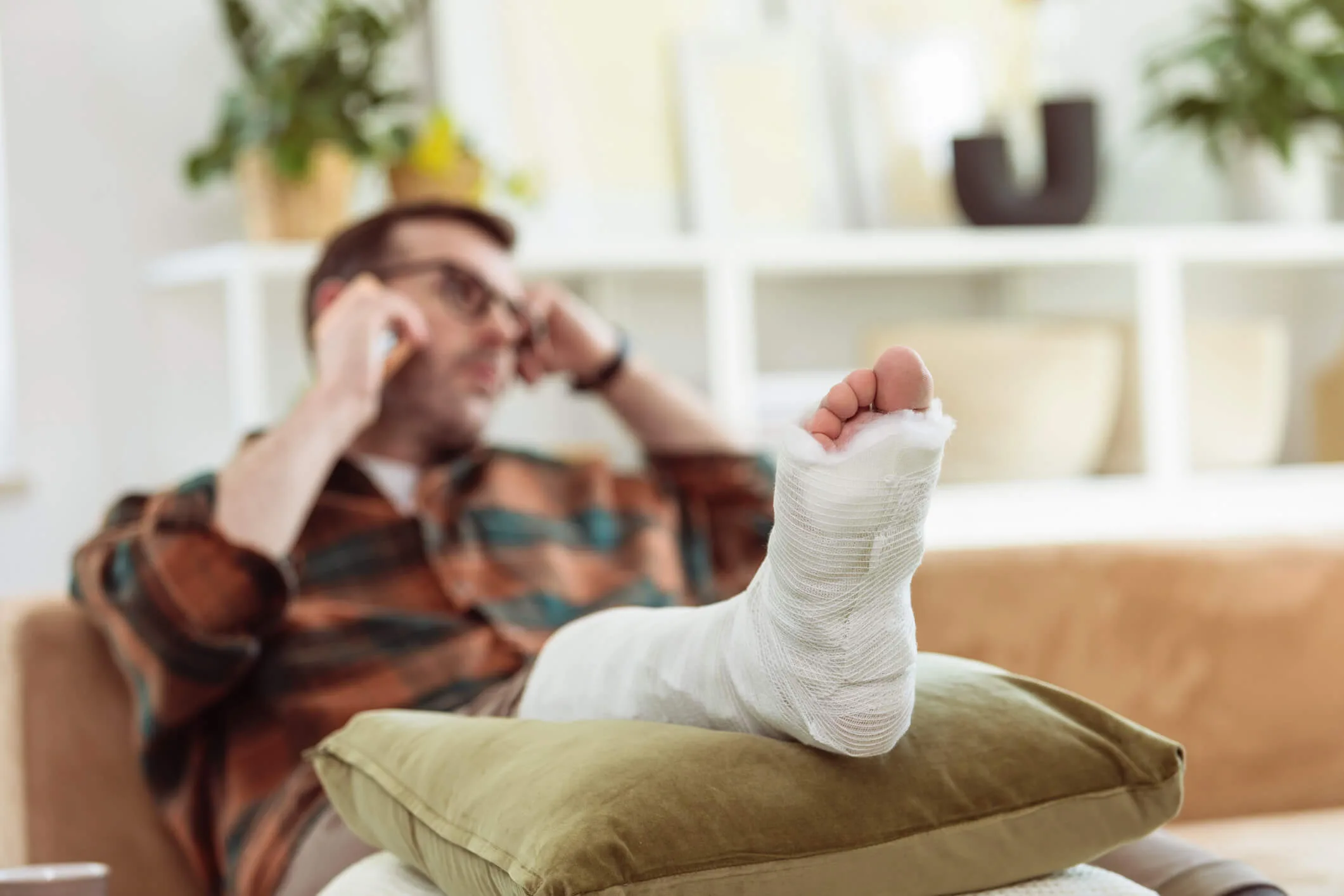 A man sitting on a couch with his leg in a cast elevated