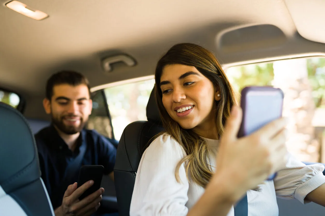 a man and woman driving in the car holding cellphones